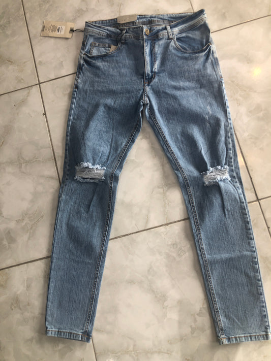 Jean caballero azul claro roto en rodilla borde café